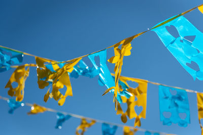 Low angle view of flags hanging against blue sky