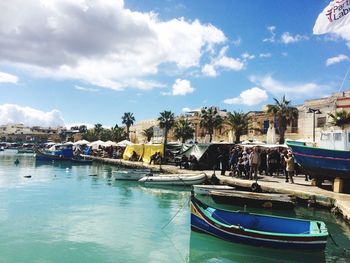 Boats moored at harbor against sky