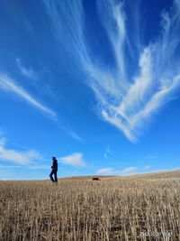 Man standing on field against blue sky
