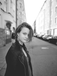 Portrait of young woman standing on street in city