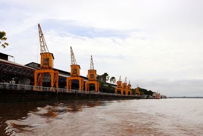 View of buildings by river against cloudy sky