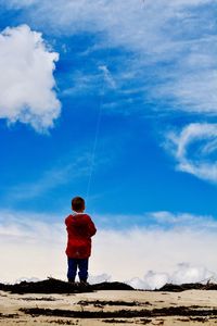 Full length of boy standing against blue sky