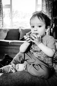 Portrait of cute boy eating fruit at home