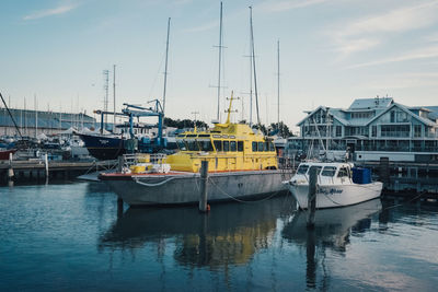 Boats moored at harbor against sky