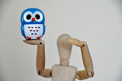 Close-up of figurine on wood against white background