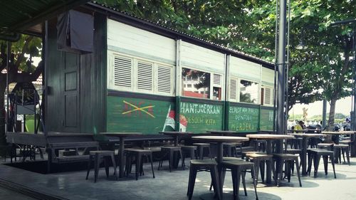 Empty chairs and tables in cafe against building