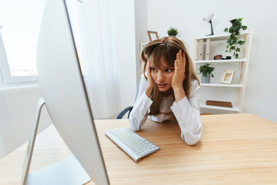 Portrait of young woman using laptop at office