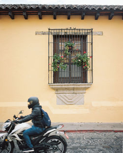 Man riding motorcycle on street against building