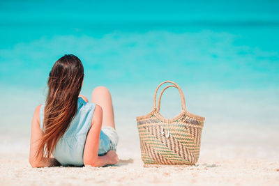 Rear view of woman relaxing on beach