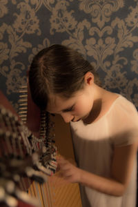 High angle view of girl playing harp against patterned wall