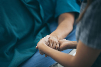 Midsection of woman holding patient hand