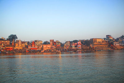 Scenic view of river by buildings against clear sky