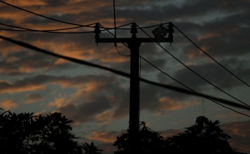 Low angle view of silhouette electric tower against sky at sunset