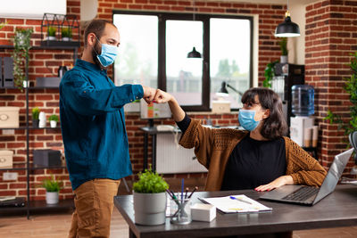 Business colleagues bumping fists at office