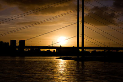 Silhouette of bridge over river during sunset