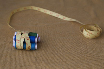 Close-up of threads wrapped in tape measure on table