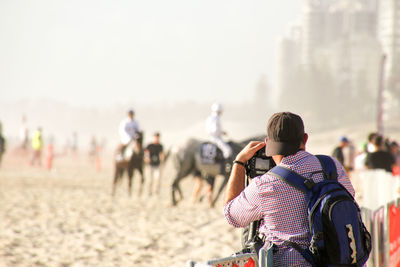 Rear view of people on beach against sky