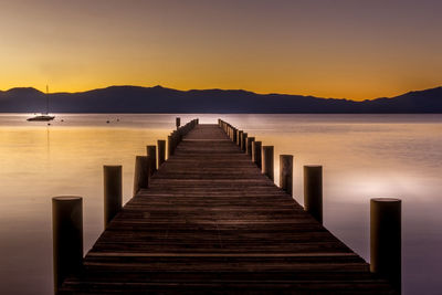 Pier over lake against sky during sunset