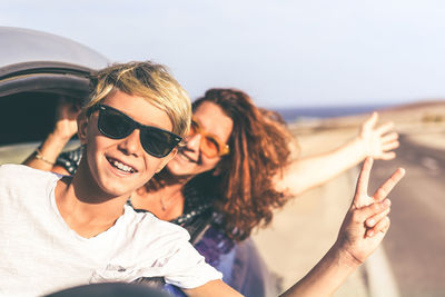 Portrait of smiling young woman on beach against sky