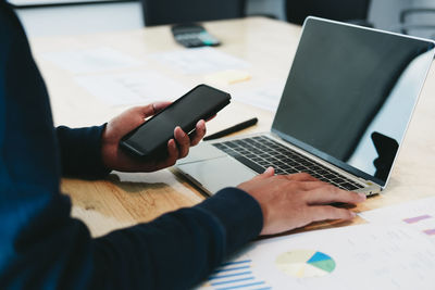 Midsection of man using laptop on table