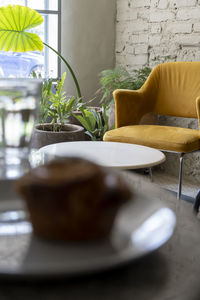 Pancake or cupcake on ceramic plate, terrazzo table, in the background out of focus armchairs and 