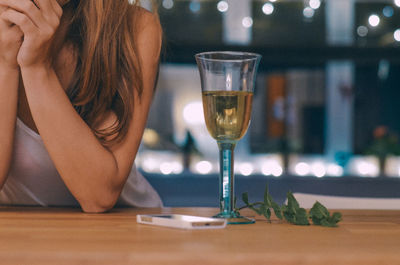 Midsection of woman drinking glass on table at restaurant