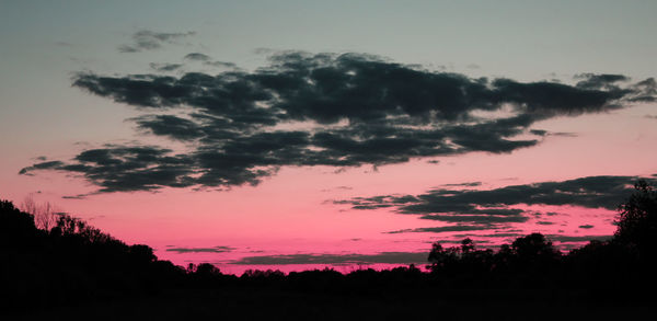 Silhouette trees on landscape against sky at sunset