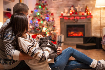 Rear view of woman with dog sitting on christmas tree