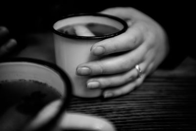 Close-up of woman holding coffee cup on table