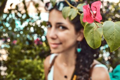 Portrait of woman with pink flowers against blurred background