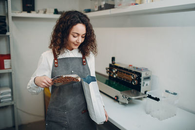 Young woman looking away while standing in kitchen