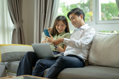 Friends sitting on sofa at home