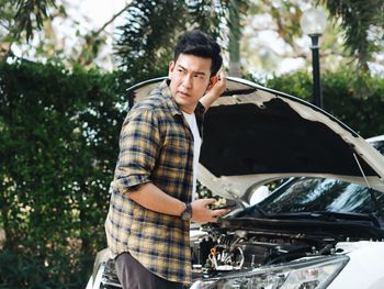 Young man standing by car