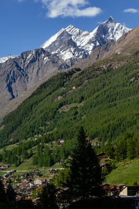 Snow capped rothorn summit view with snow valley with typical swiss wooden chalet houses and trees