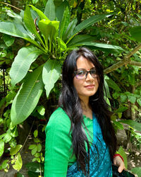Portrait of young woman standing against plants