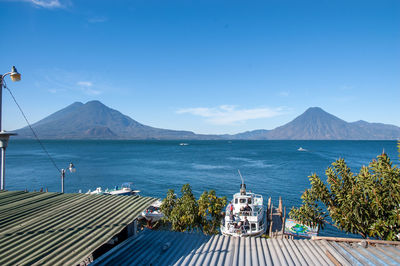 Scenic view of lake atitlan and volcanos against blue sky