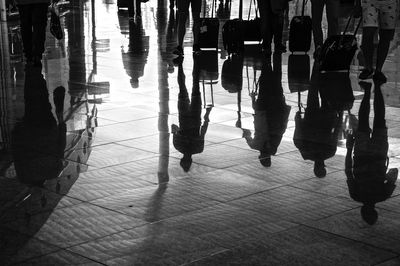 Reflection of people with luggage on floor at airport