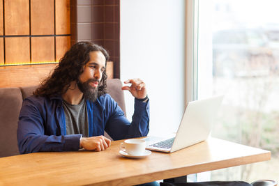 Young woman using mobile phone while sitting on table