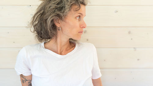 Mid adult woman looking away while standing against wall