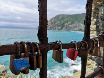 Close-up of padlocks on railing against sea