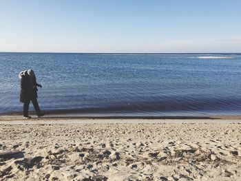 Rear view of woman on beach against clear sky