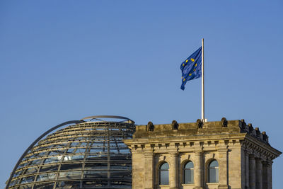 Low angle view of flags against clear blue sky