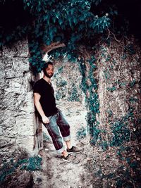 Portrait of young man looking away against tree