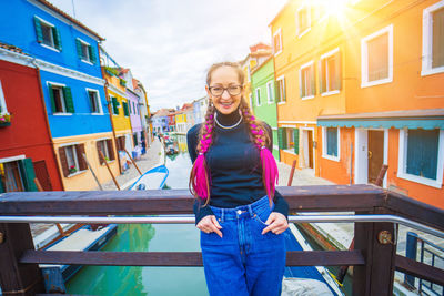 Portrait of young woman standing against buildings