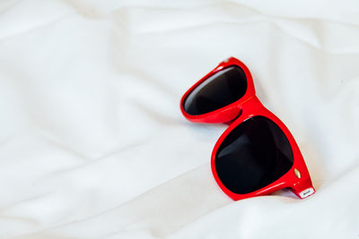 High angle view of red sunglasses on white sheet