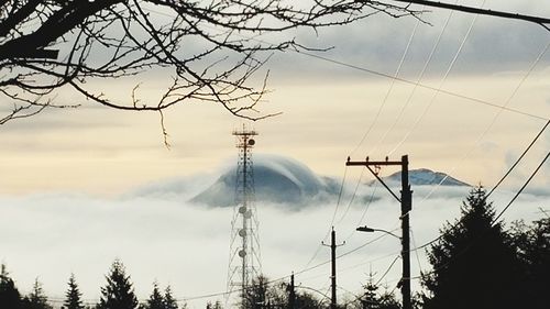 Low angle view of electricity pylon against cloudy sky