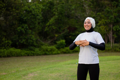 Portrait of a smiling young woman standing on field