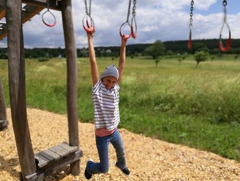 Portrait of smiling girl hanging on gymnastic rings