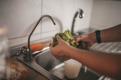 Midsection of man holding faucet at home