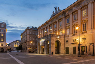 Street amidst buildings against sky at dusk